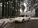 1989 Nissan 300ZX - A white 1989 Nissan 300ZX sits on a wet, snow-dusted road surrounded by a dense forest.