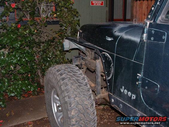 Dark green 1994 Jeep YJ front fender removed, showing exposed frame and large tire