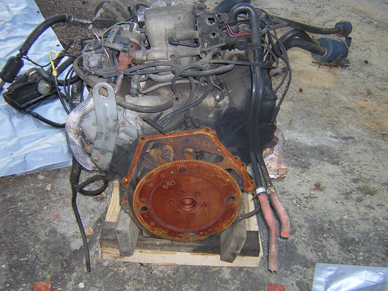 Engine block with rusty flywheel, sitting on wooden blocks
