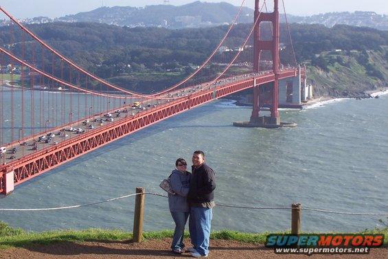 Couple posing for photo with Golden Gate Bridge and traffic in background