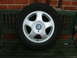 2001 Ford Fiesta - A single Vauxhall wheel and tire rests on a wooden bench in front of a brick wall.