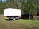 1994 Ford F-150 - A black pickup truck tows a trailer carrying a large, white, modular structure, marked as an oversized load.