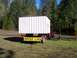 1994 Ford F-150 - A trailer carries a shed, marked as an oversize load, in an outdoor setting.