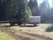 1994 Ford F-150 - A black 1994 Ford F-150 is seen from the side, towing a large white cargo trailer through a grassy, wooded area.
