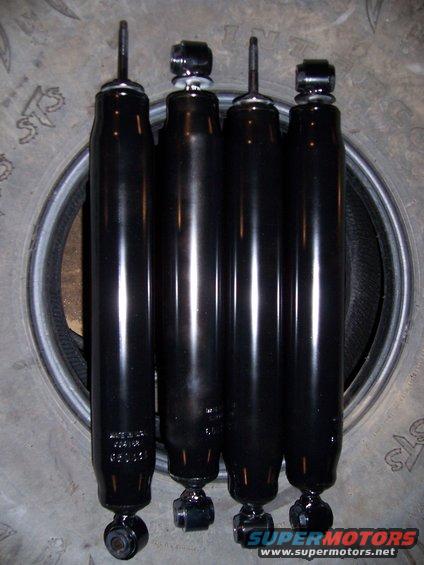 Four black shock absorbers resting on a tire. Text on one shock reads 'Made in USA'