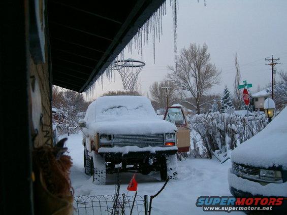 1985 Ford Bronco and another SUV covered in snow, parked outside
