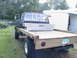 1977 Ford F-250 - This 1977 Ford F-250 flatbed truck features a custom wooden bed and a large silver toolbox mounted behind the cab.