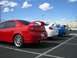 1996 Ford Probe - Three Dodge Neon SRT-4s are parked in a lot, with the red one in the foreground showing its distinctive rear spoiler and dual exhaust pipes.