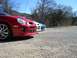 1996 Ford Probe - Three cars are parked in a gravel lot under a clear blue sky with trees in the background.