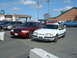 1987 Ford Mustang - Two cars are parked in a lot, one is a white Ford Mustang and the other is a red Ford Crown Victoria.