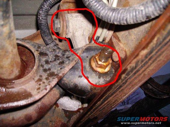 Rusted suspension part with bolt and wiring, circled in red