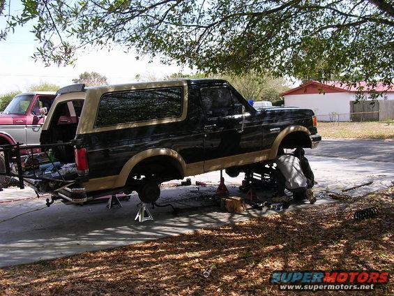 1988 Ford Bronco on jack stands with suspension work underway; another vehicle partially visible to the left