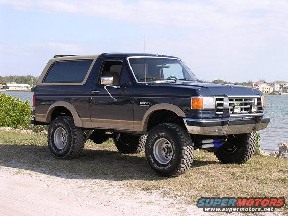 1988 Ford Bronco lifted with off-road tires parked near water