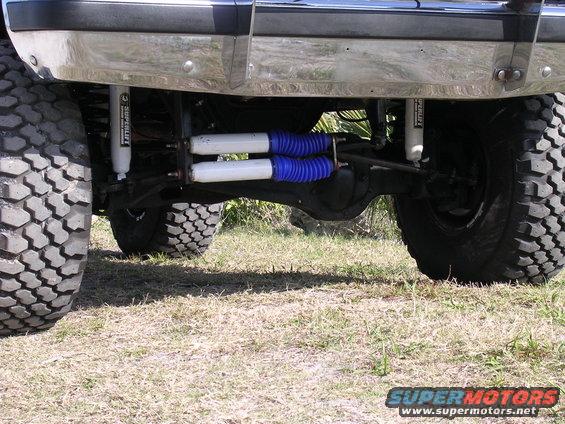 Rear axle with dual shocks and large tires. Supermotors.net logo visible