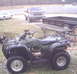 2005 Honda RANCHER - Side view of a 2005 Honda Rancher ATV. A Ford truck and trailer are visible in the background.