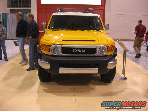 Yellow Toyota FJ Cruiser with white roof, front view. Toyota badge visible on grille
