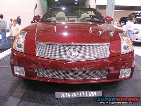 Red convertible Cadillac front view with chrome grille and badge