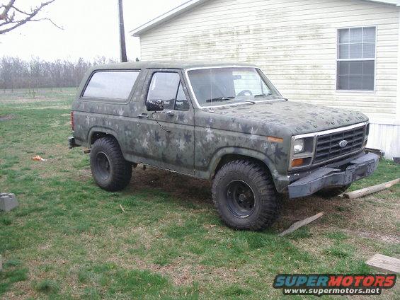 Camouflaged SUV parked in a grassy yard, front quarter view