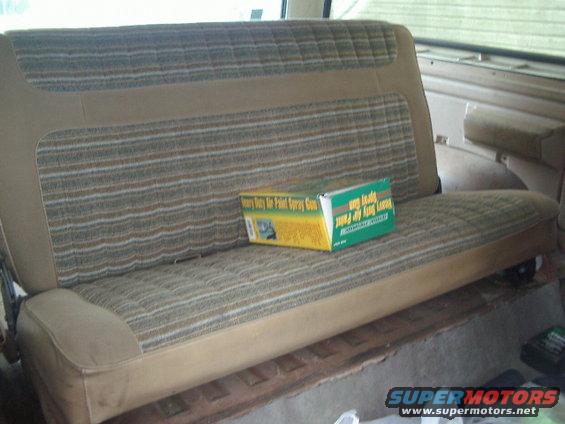Rear bench seat with striped fabric and a box of spray paint on it