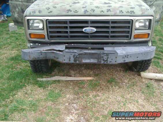 Front view of a 1980 Ford Bronco with a damaged bumper and camouflage paint