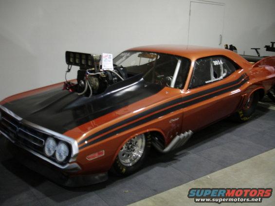 Orange drag car with black stripes, hood scoop, and side pipes