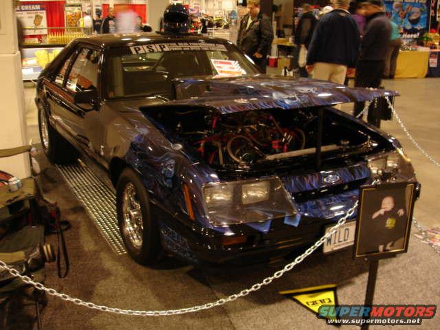 1981 Ford Mustang with custom paint and open hood showing engine. License plate reads WILD