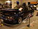 1981 Ford Mustang - A customized black Ford Mustang, identified as a 1985 model, is displayed with its hood open, revealing the engine and custom airbrushed gr…