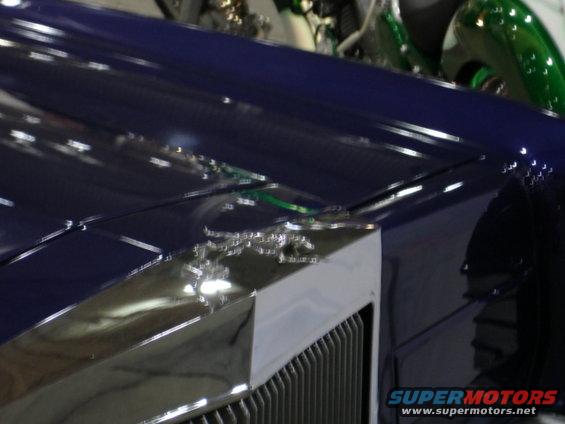 Blue car hood with chrome trim and visible Supermotors.net watermark