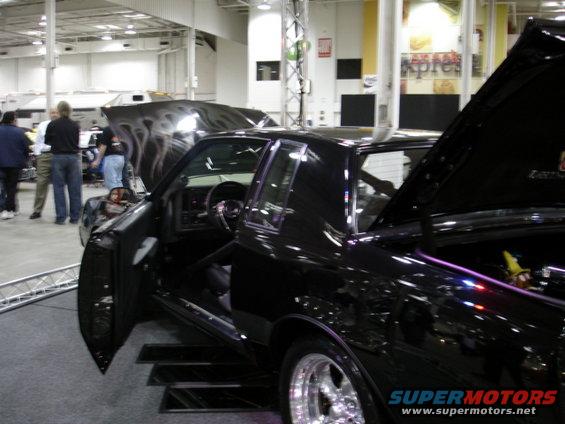 black coupe with custom flames on hood, doors open, interior visible