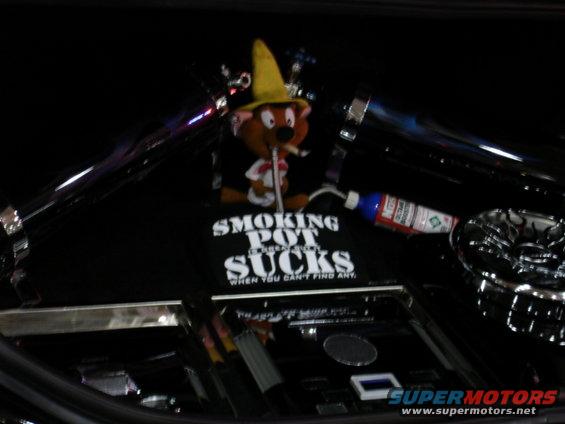 Cartoon character with a yellow hat and cigarette, on a black surface with text and a bottle