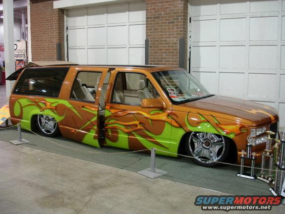 Customized SUV with orange and green flame graphics, lowered suspension, and chrome wheels