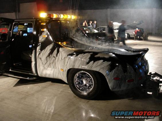 Custom tow truck with unique grey and black paint, chrome wheels, and amber lights