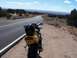 2000 Honda CBR-RR - A yellow motorcycle with a black helmet rests on the shoulder of a winding road, overlooking a distant valley.