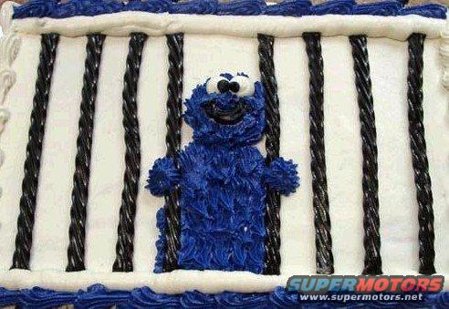 Cookie Monster character made of blue frosting behind black licorice bars on a white cake
