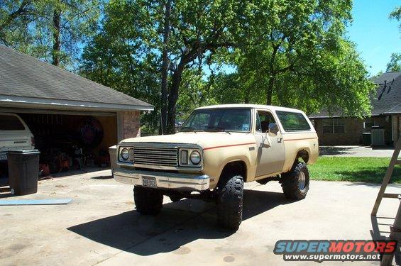 tan Dodge Ramcharger with lifted suspension and large tires parked in a driveway