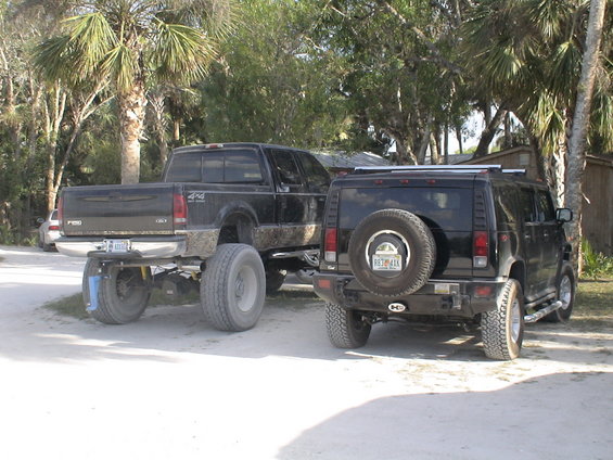 Black pickup truck with large tires and a black SUV parked side-by-side