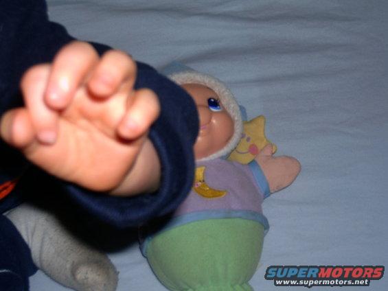 Baby's hand reaching towards a stuffed toy with a moon and star