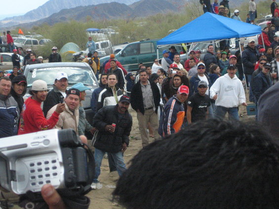 Crowd of spectators in the desert with a man filming on a camcorder