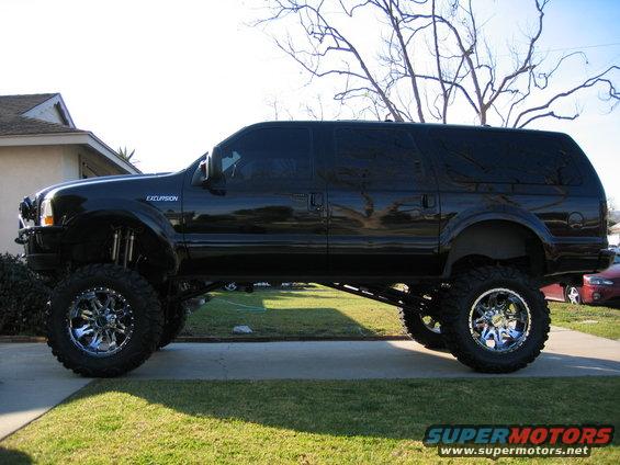 Black Ford Excursion with a massive lift kit and chrome wheels parked in a driveway