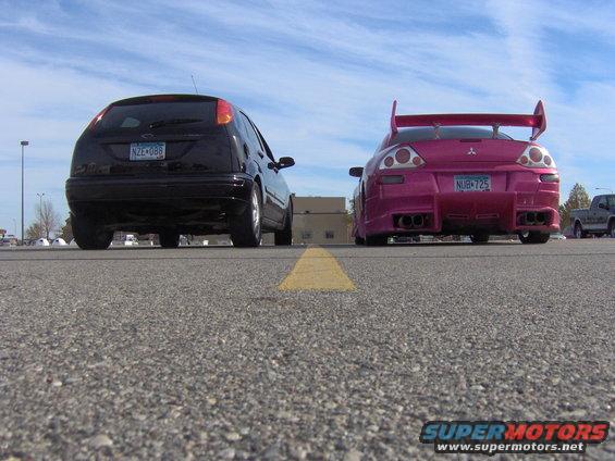 2002 Ford Focus and a pink Mitsubishi Eclipse parked side-by-side, rear view