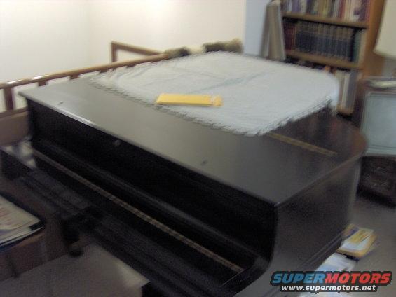 Grand piano with a light-colored cover and a yellow envelope on top