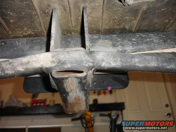 Close-up of a vehicle's tow hitch receiver, showing rust and dirt