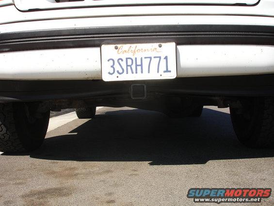 White vehicle rear bumper with California license plate 3SRH771 and a tow hitch receiver