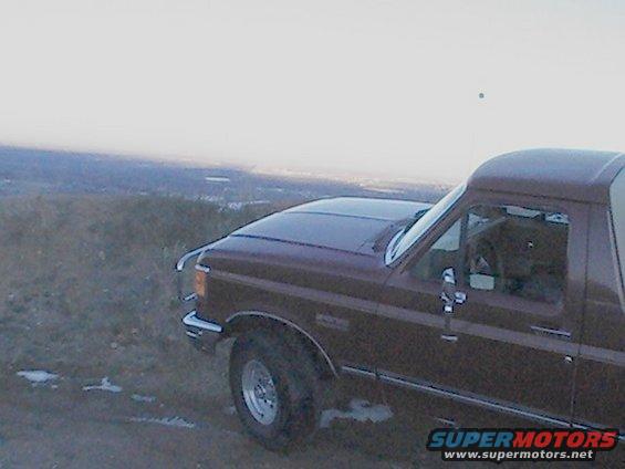 Maroon Ford Bronco parked on a hill, showing the front quarter panel and driver's side door