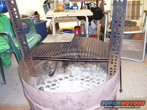 Grill with perforated metal sides and ash-filled base