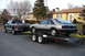 1981 Ford Mustang - Pickup truck tows trailer with a 1980s Ford Mustang hatchback, as a man secures it with a strap.