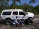 2000 Ford Excursion - A lifted 2000 Ford Excursion is parked off-road with several people inside and a dirt bike positioned in front of it.