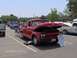 1960 Ford F-100 - A red 1960 Ford F-100 pickup truck is displayed with its hood open, alongside other vehicles at an outdoor gathering.