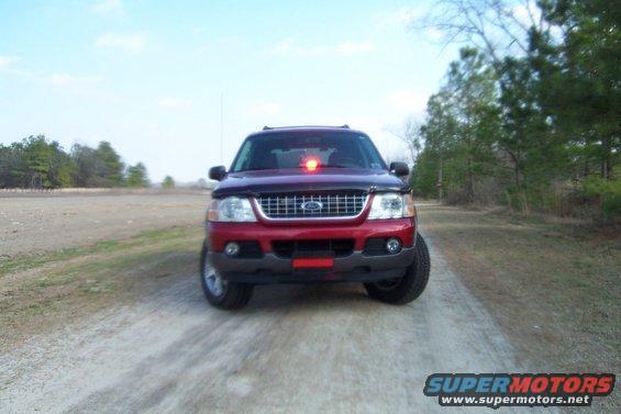 Red 2005 Ford Explorer front view on dirt road, emergency light on roof