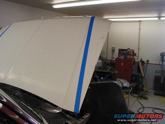 White car hood with blue tape applied down the center and on the side